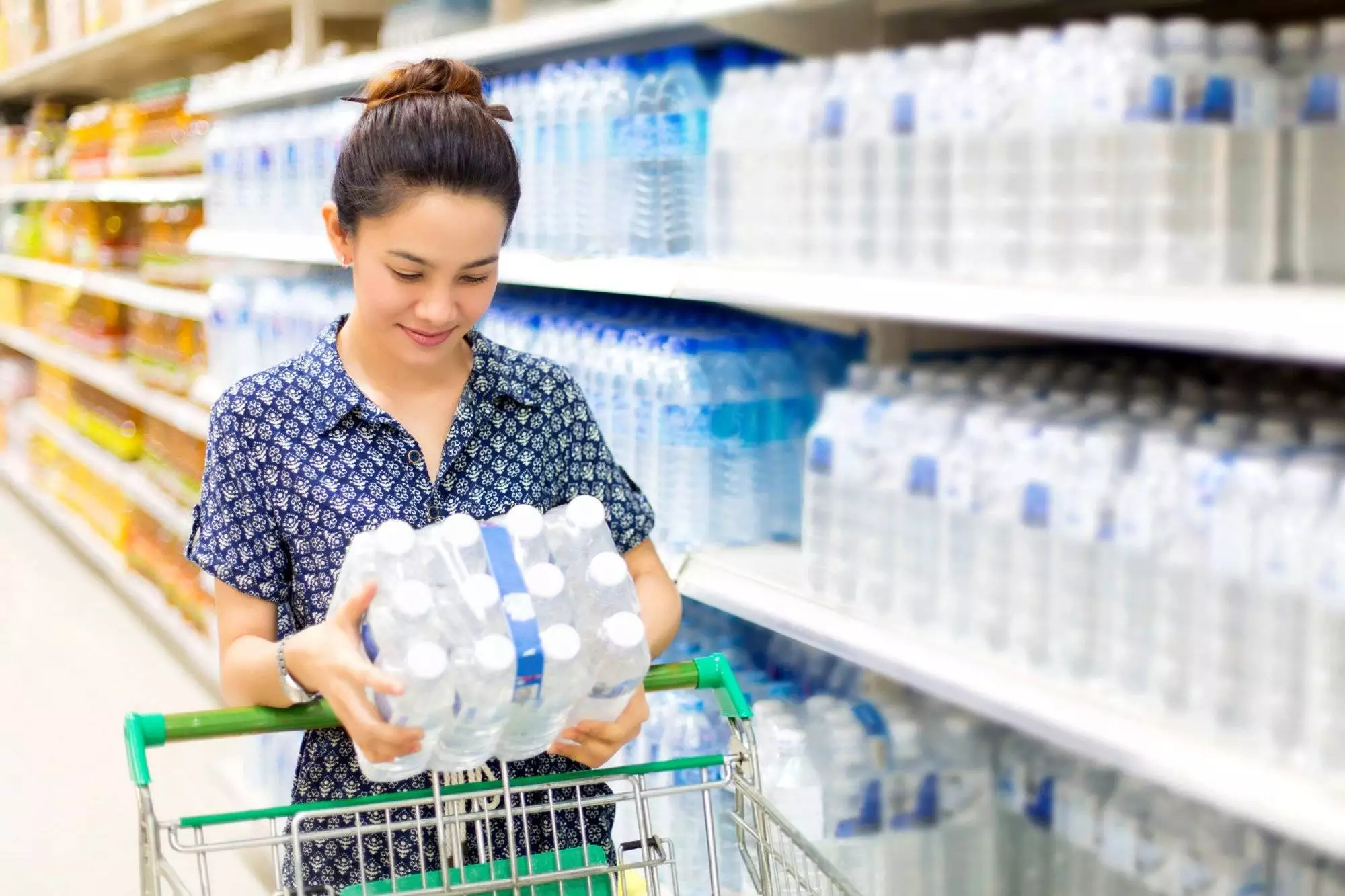 Asian woman buys in the supermarket bottle of water